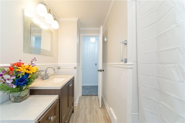 bathroom featuring a wainscoted wall, wood finished floors, vanity, and crown molding