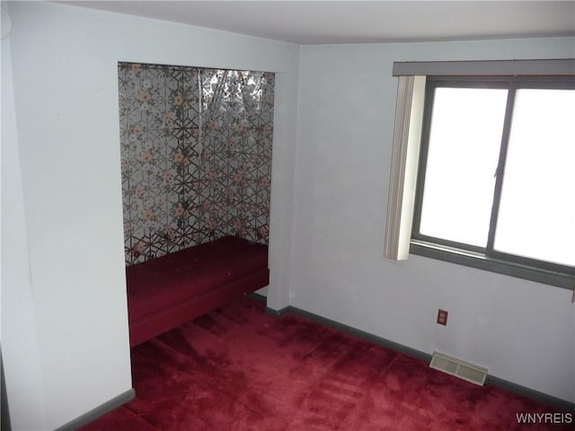 carpeted spare room featuring plenty of natural light and visible vents