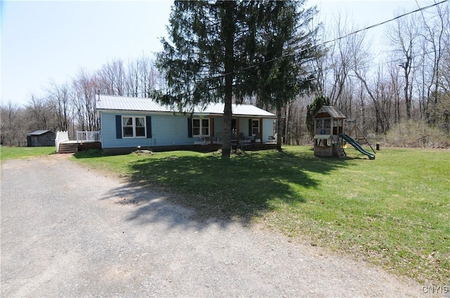 manufactured / mobile home featuring a playground, metal roof, a front yard, and dirt driveway