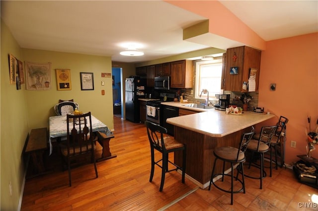 330 Hacadam Rd, Frankfort, NY 13456 - kitchen with black appliances, a sink, a breakfast bar area, a peninsula, and light countertops