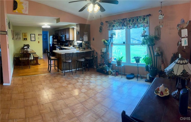 330 Hacadam Rd, Frankfort, NY 13456 - kitchen featuring ceiling fan, a kitchen bar, a peninsula, freestanding refrigerator, and vaulted ceiling