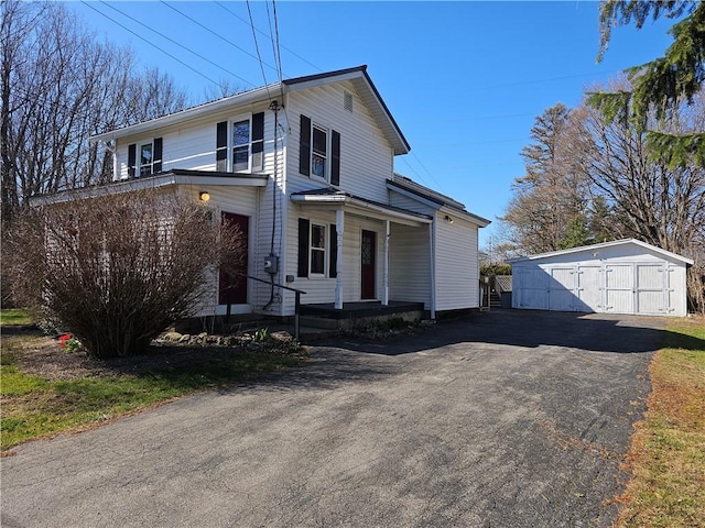 traditional home with a porch, an outbuilding, and a detached garage