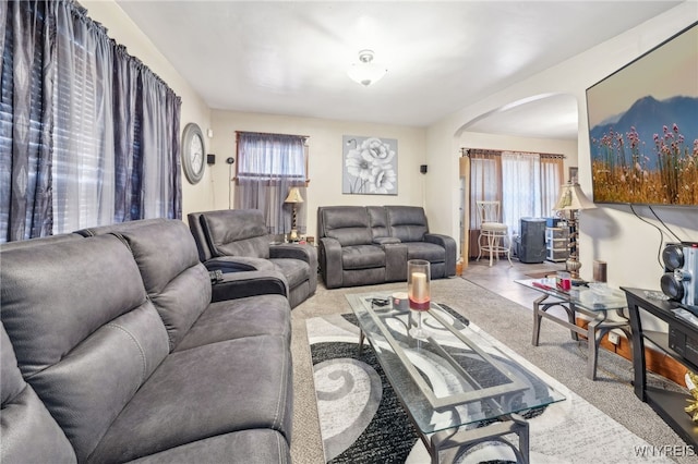 living room with arched walkways, a wealth of natural light, and carpet
