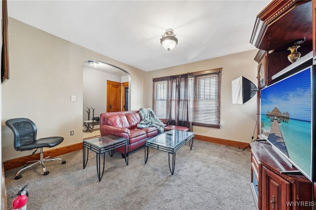 carpeted living room with baseboards and arched walkways