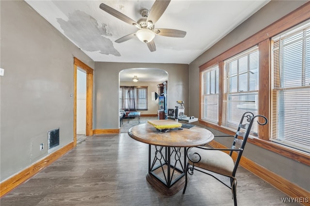 dining space featuring ceiling fan, visible vents, baseboards, arched walkways, and wood finished floors