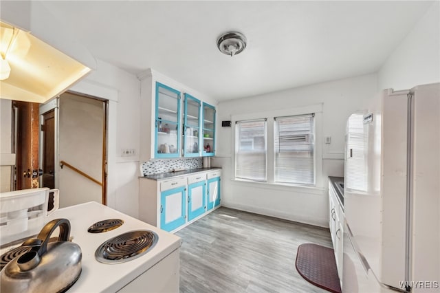 kitchen with glass insert cabinets, light wood-style flooring, blue cabinetry, and white appliances