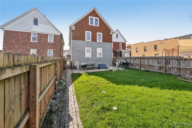 rear view of house featuring a lawn, a patio, and a fenced backyard