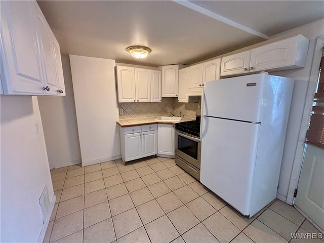 kitchen with stainless steel gas stove, light tile patterned floors, white cabinets, and freestanding refrigerator