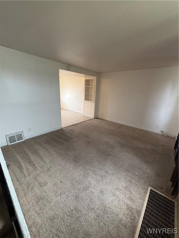 unfurnished living room featuring carpet floors and visible vents