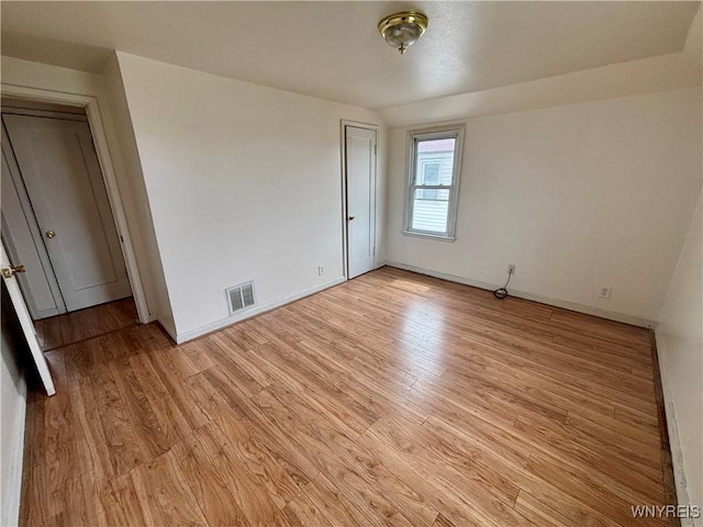 unfurnished room featuring light wood-type flooring, visible vents, and baseboards