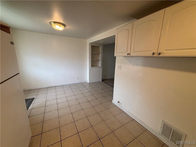 unfurnished dining area featuring light tile patterned flooring, baseboards, visible vents, and built in shelves