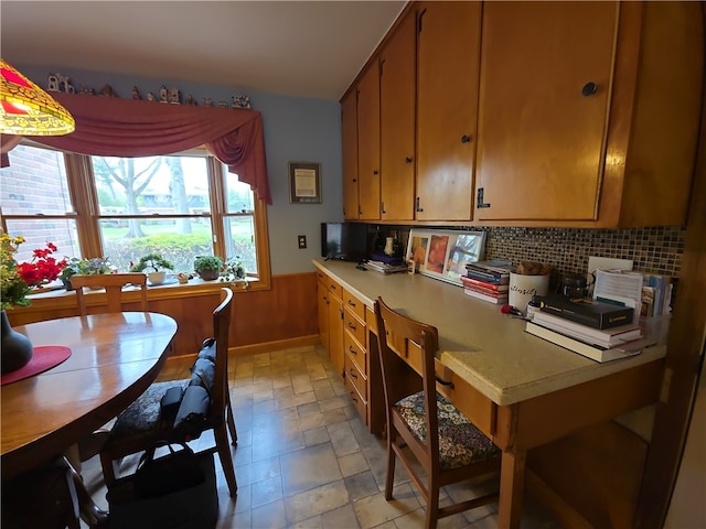 658 Cornell Rd, Elmira-City, NY 14905 - kitchen with light countertops, brown cabinets, a wainscoted wall, and tasteful backsplash