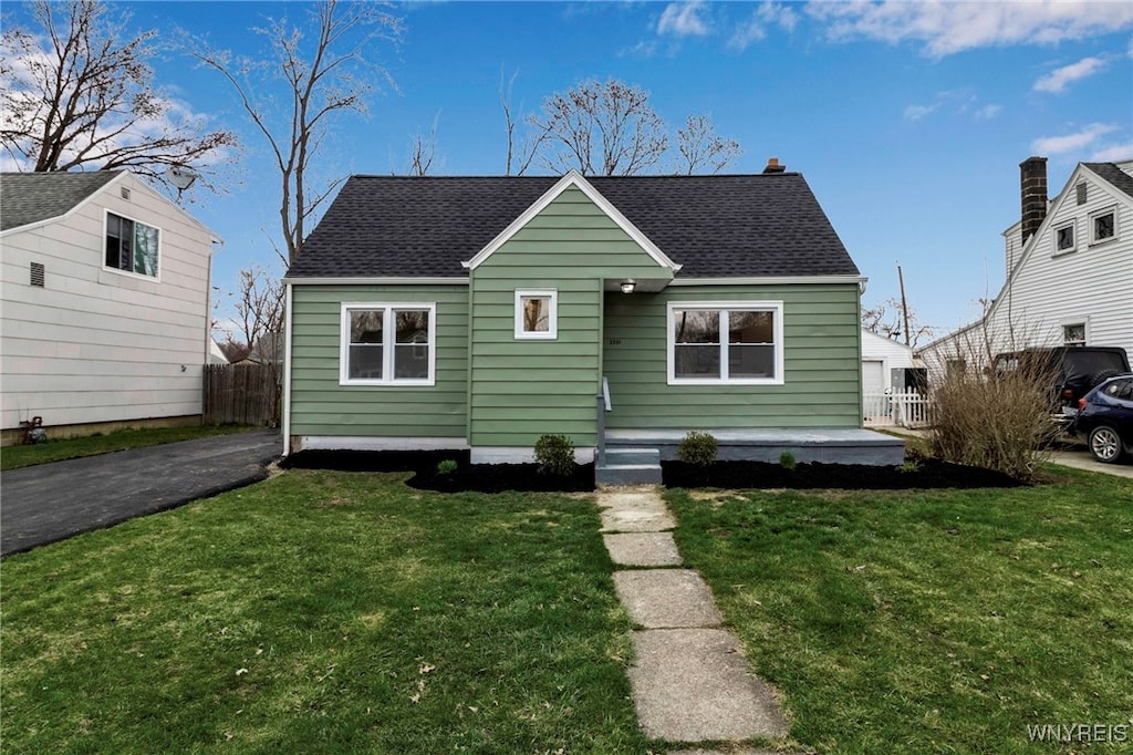 bungalow-style house with roof with shingles, a front yard, and fence