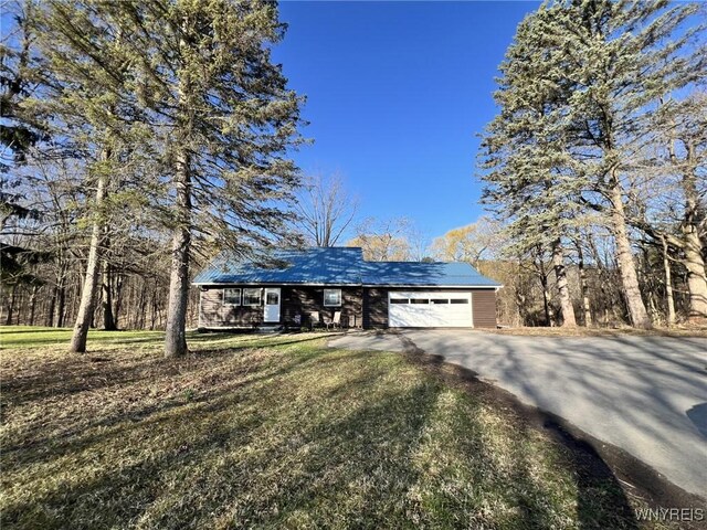 view of front of home featuring a front lawn, driveway, a garage, and metal roof