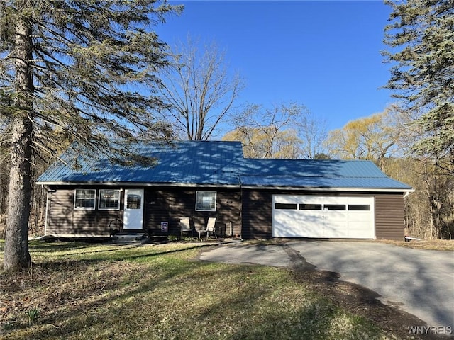 single story home featuring entry steps, an attached garage, aphalt driveway, and metal roof