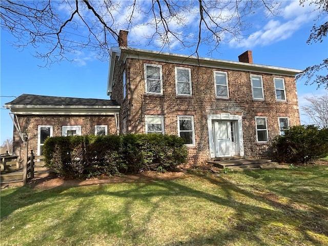 colonial house with a chimney, brick siding, and a front yard