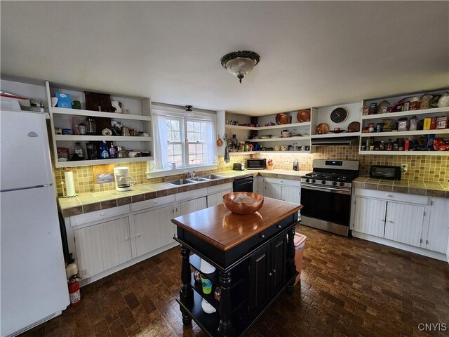 kitchen with gas range, dishwasher, open shelves, and freestanding refrigerator