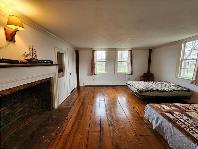 bedroom featuring wood-type flooring, a fireplace, baseboards, and ornamental molding