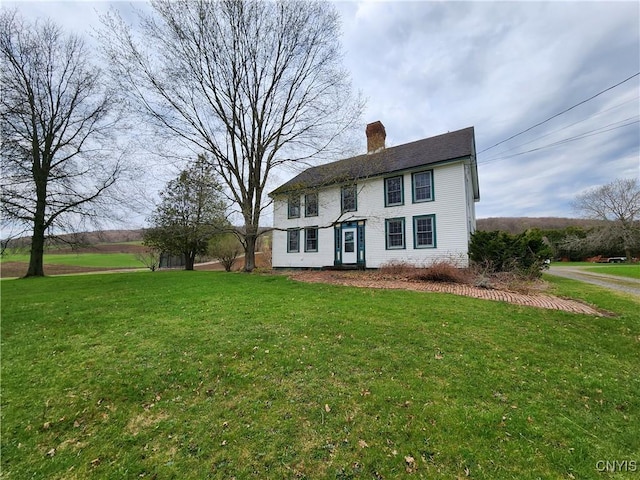 colonial home with a chimney and a front lawn