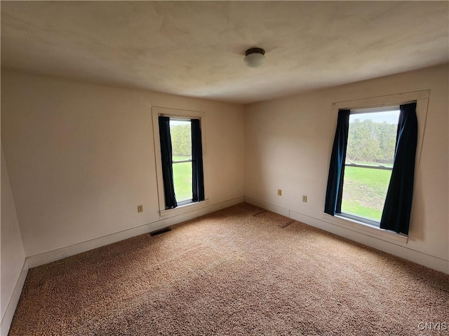 empty room featuring light carpet, visible vents, and baseboards
