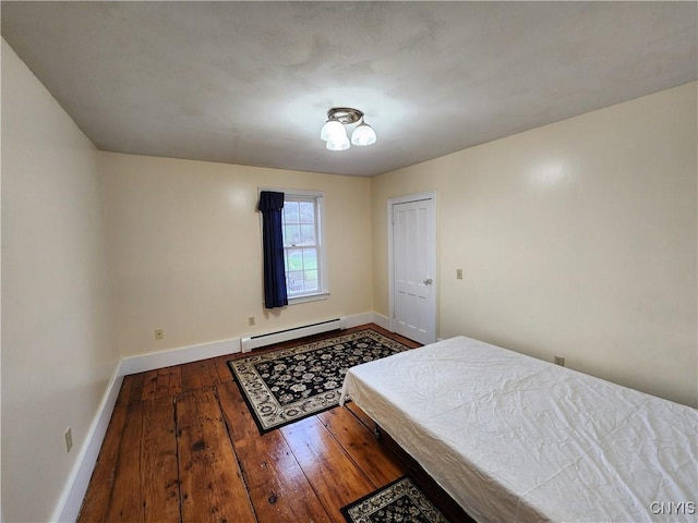 bedroom with a baseboard heating unit, wood-type flooring, and baseboards