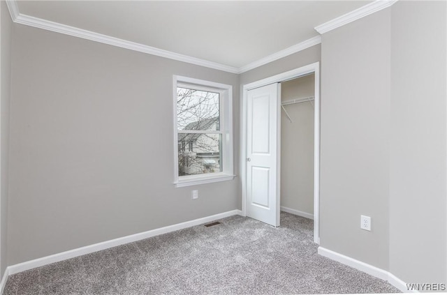 unfurnished bedroom featuring a closet, baseboards, crown molding, and carpet