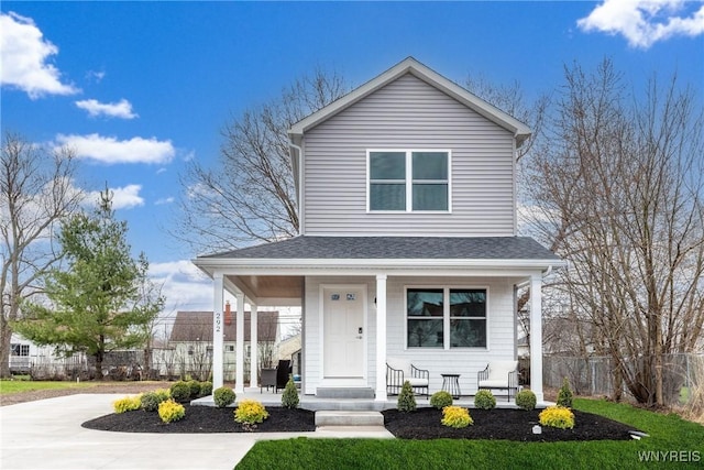 view of front facade featuring roof with shingles, a porch, concrete driveway, and fence