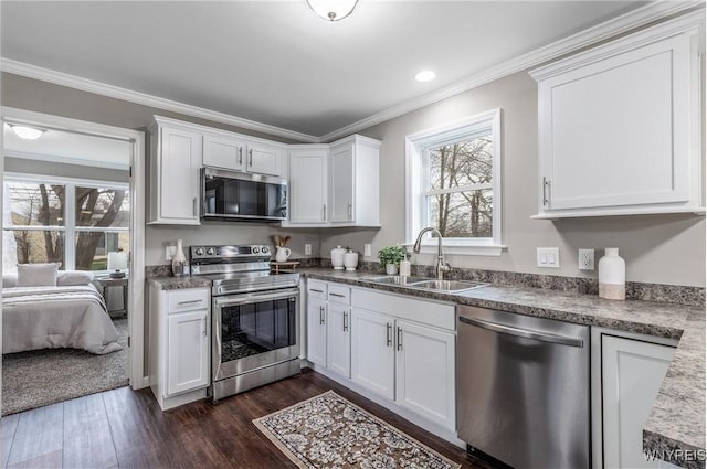 kitchen featuring stainless steel appliances, a sink, dark wood-type flooring, crown molding, and white cabinetry