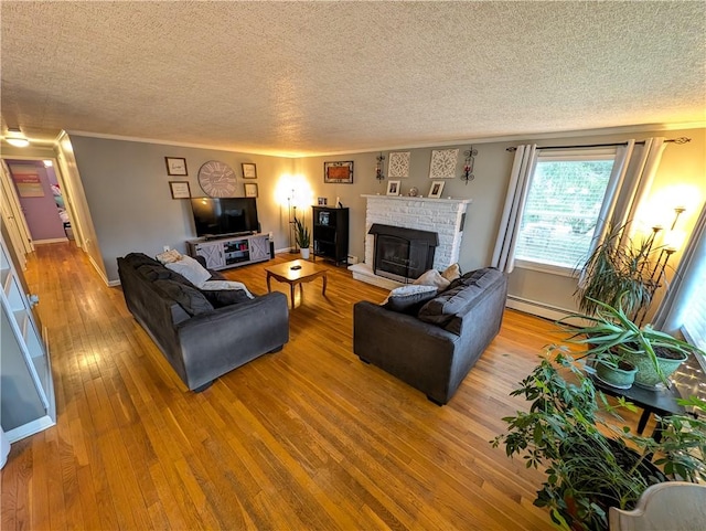 living room featuring baseboard heating, baseboards, a textured ceiling, and light wood-style floors