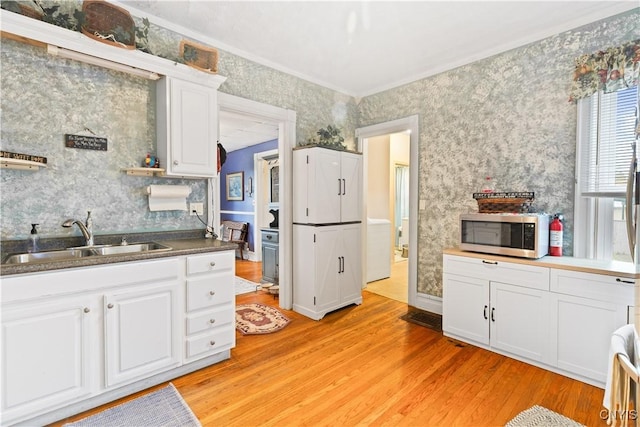 601 W Thomas St, Rome-Inside, NY 13440 - kitchen featuring white cabinets, wallpapered walls, light wood finished floors, a sink, and stainless steel microwave