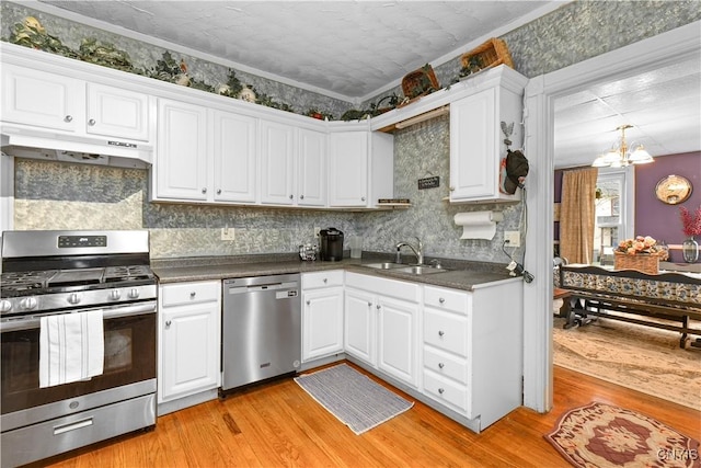 601 W Thomas St, Rome-Inside, NY 13440 - kitchen with under cabinet range hood, dark countertops, a sink, a chandelier, and appliances with stainless steel finishes