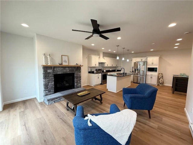 2002 Maes Lndg, Canandaigua-Town, NY 14424 - living area with a stone fireplace, a ceiling fan, baseboards, and light wood-type flooring