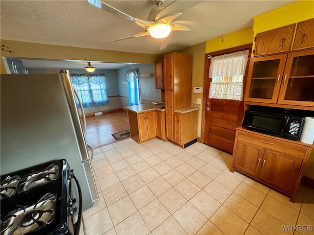 1432 Quaker Rd, Somerset, NY 14012 - kitchen with brown cabinets, black microwave, a peninsula, and freestanding refrigerator
