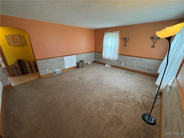 1432 Quaker Rd, Somerset, NY 14012 - unfurnished room featuring a wainscoted wall, arched walkways, a textured ceiling, visible vents, and carpet