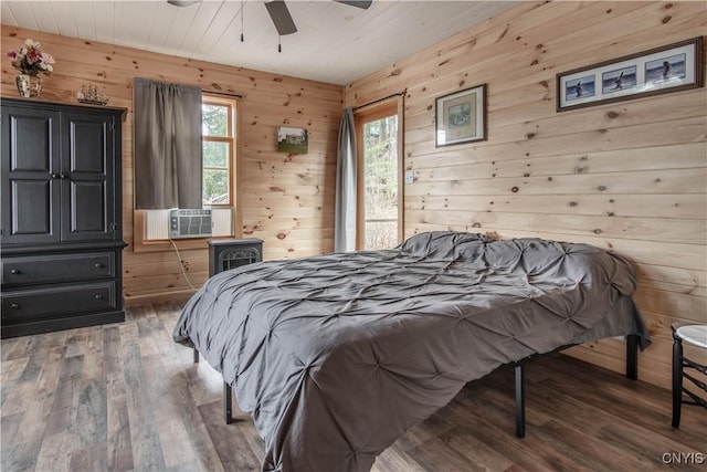 bedroom featuring ceiling fan, wood walls, wood finished floors, and cooling unit