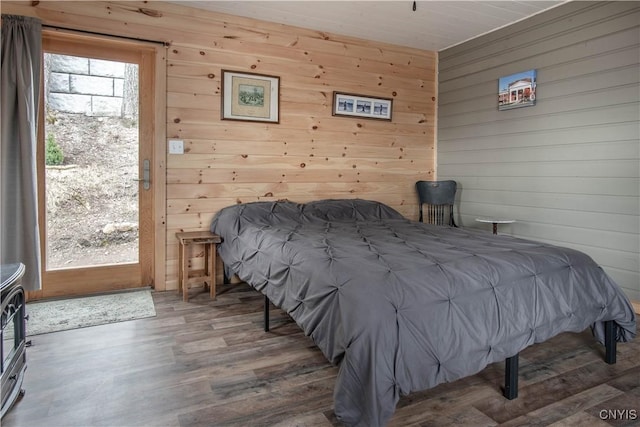 bedroom with wood finished floors, access to exterior, and wood walls