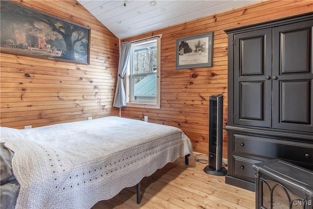 bedroom featuring light wood finished floors, vaulted ceiling, and wooden walls