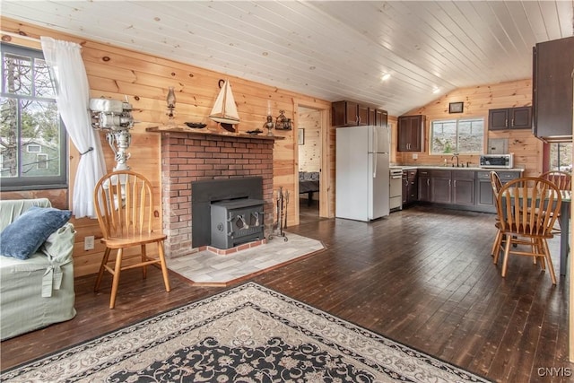 living area featuring wood walls, lofted ceiling, a wood stove, and dark wood-style floors