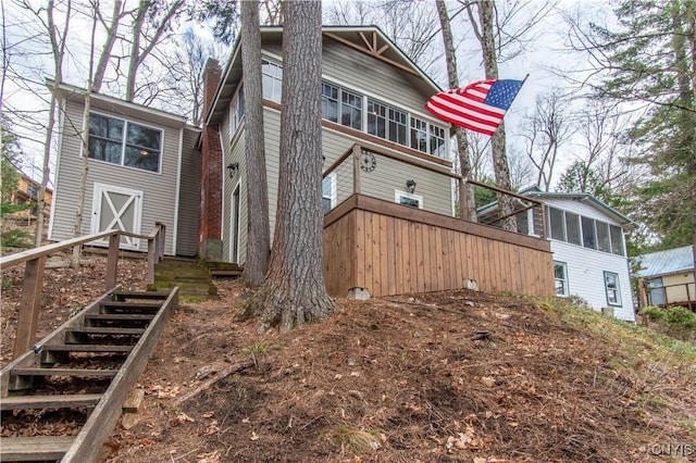view of home's exterior with stairs, a sunroom, and a chimney