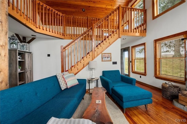 living area with a towering ceiling, baseboards, wood finished floors, and stairway