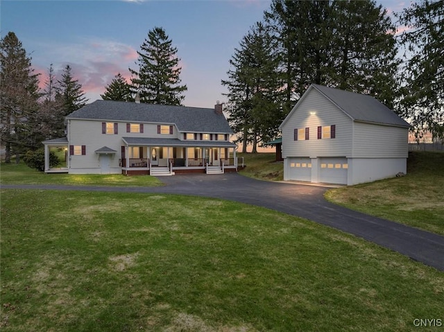 view of front of home with covered porch, a yard, and a garage