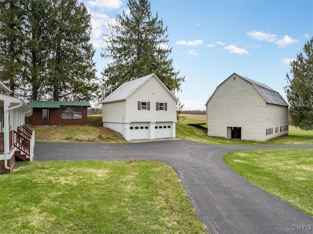 exterior space featuring a gambrel roof, an outbuilding, a yard, and a garage