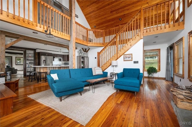 living room featuring hardwood / wood-style flooring, baseboards, a towering ceiling, and stairway