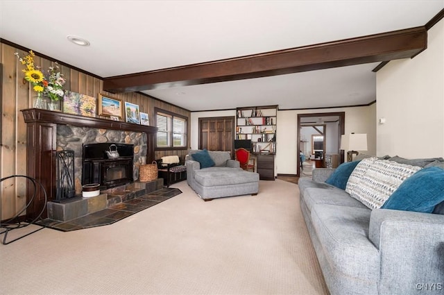 living room with a wood stove, beamed ceiling, wood walls, ornamental molding, and carpet flooring