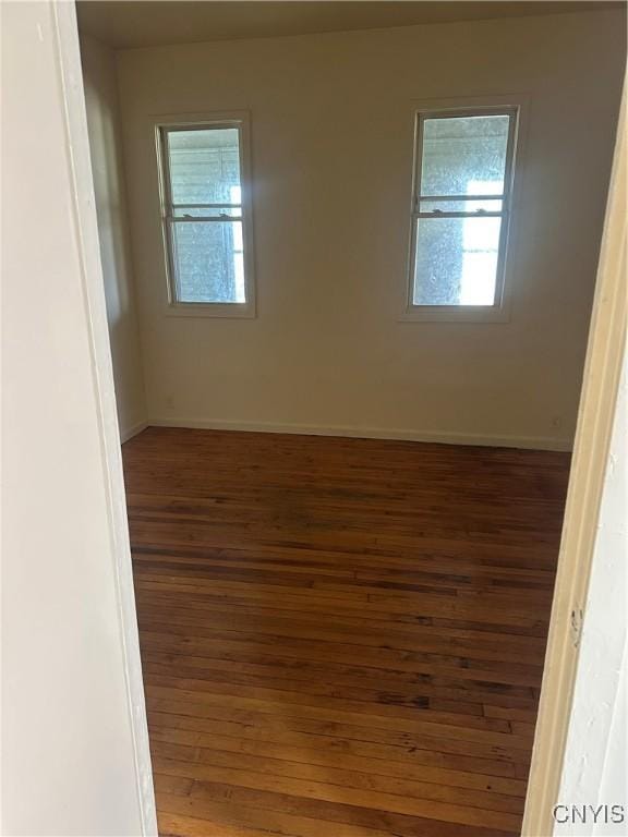 spare room with baseboards and hardwood / wood-style flooring