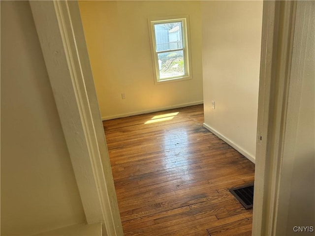 empty room featuring baseboards, visible vents, and wood-type flooring