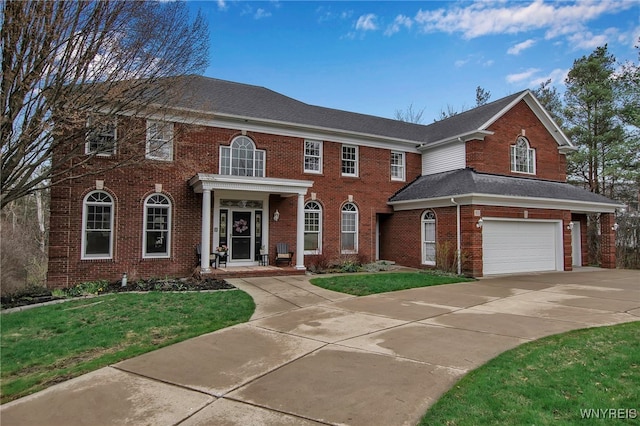 georgian-style home with a shingled roof, concrete driveway, brick siding, a front yard, and a garage