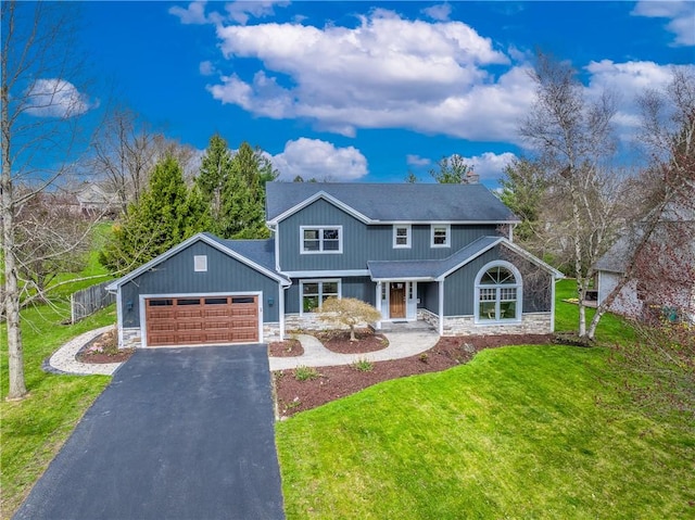 view of front of property featuring a front lawn, stone siding, fence, an attached garage, and aphalt driveway