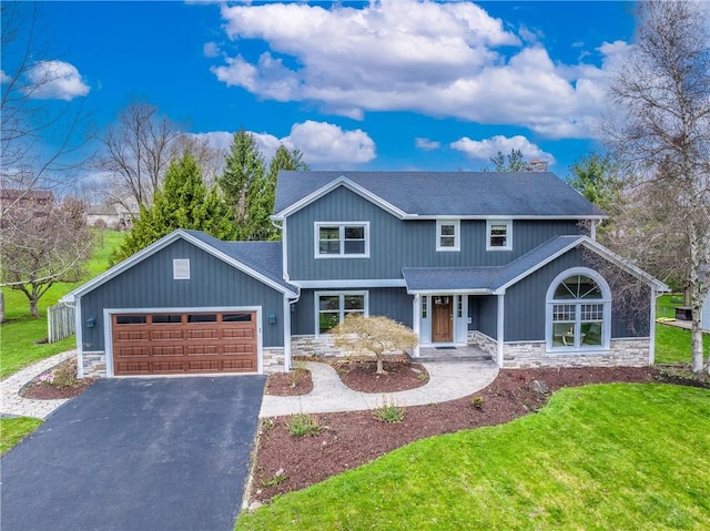 view of front facade with stone siding, driveway, a front yard, and a garage