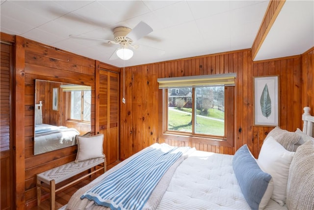 bedroom with wood walls and a ceiling fan